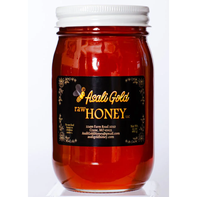 Jar of Asali Gold raw honey on a white background
