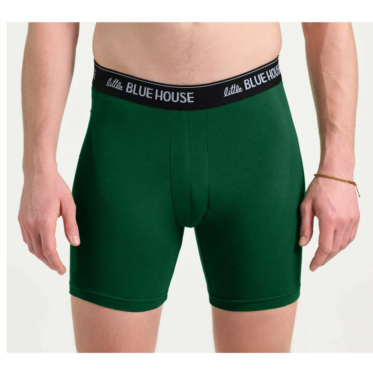 A man wearing dark green boxer briefs with a black elastic waistband featuring the white 'little BLUE HOUSE' logo, shown from the waist down against a light gray background.