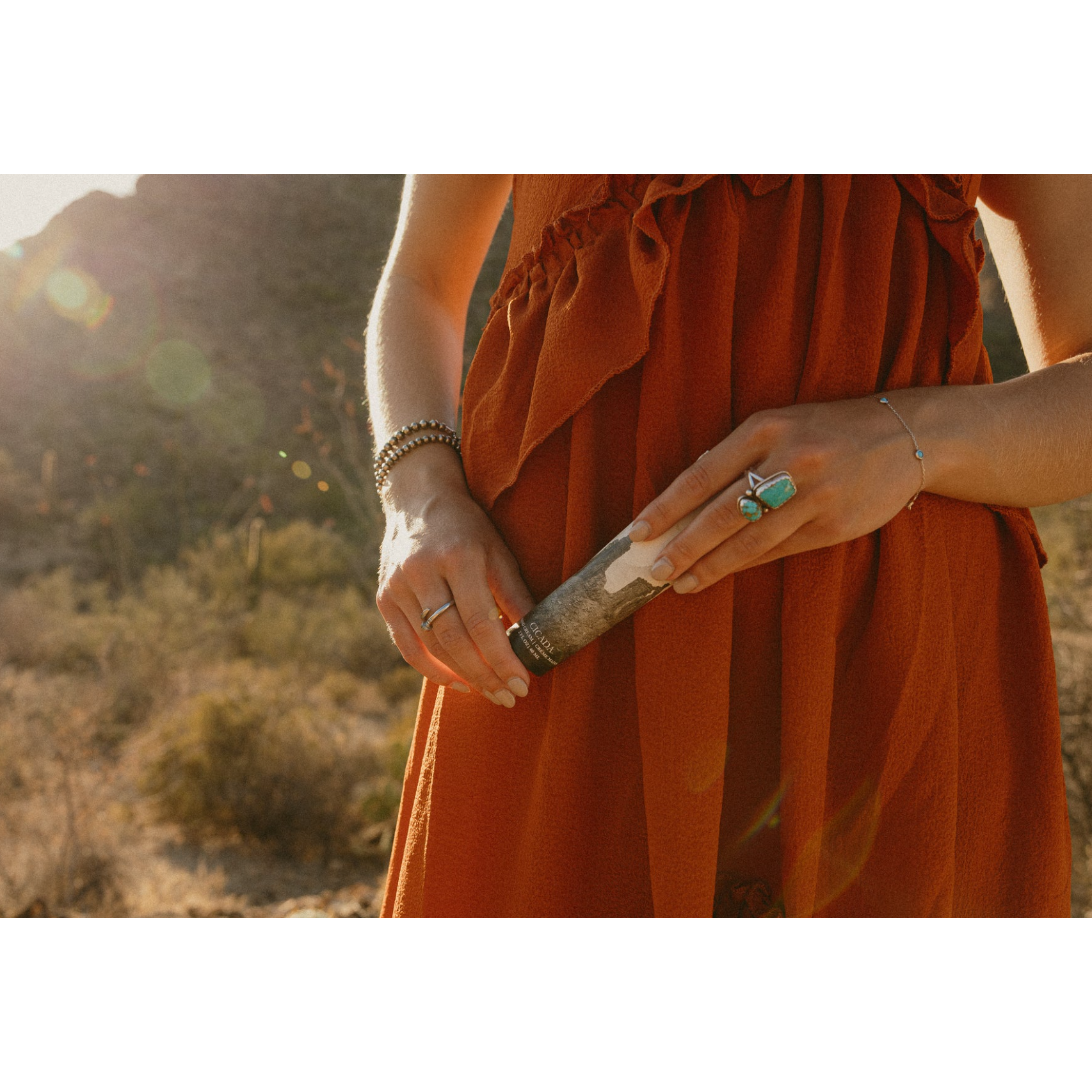 Person in an orange dress holding a walking stick in a natural setting