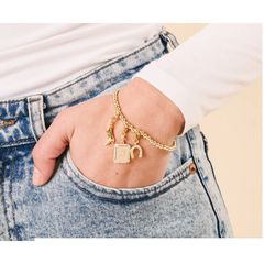 Gold bracelet with charms on a wrist against a denim background