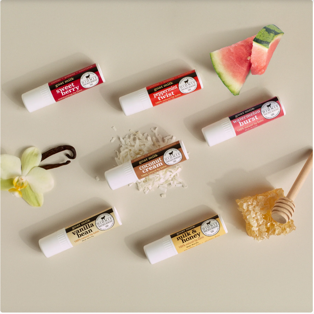 Various lip balm tubes with different flavors on a neutral background, featuring a slice of watermelon and honeycomb.