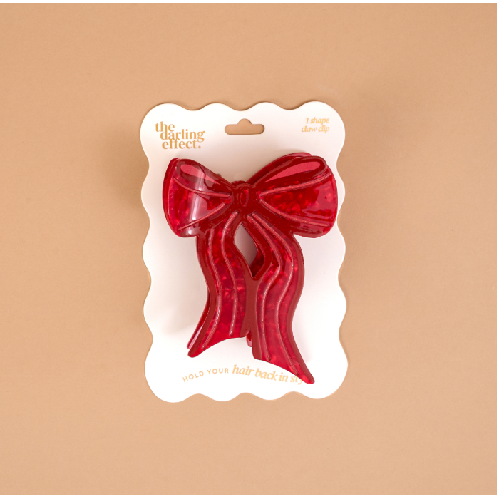 A red translucent hair bow accessory in its white retail packaging, displayed against a solid beige background. The packaging features the brand name 'the diting effect' in gold lettering.