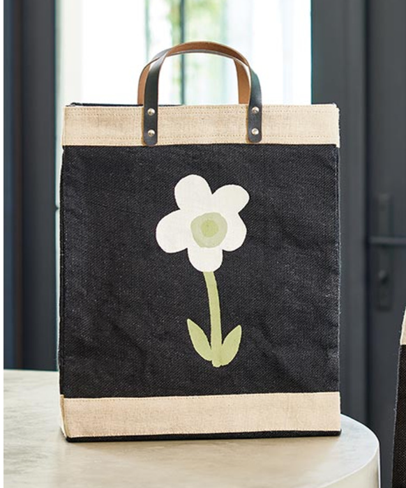 Black tote bag with a white flower design on a wooden surface