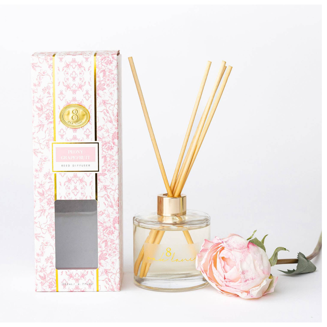Reed diffuser set with packaging and a pink flower on a white background