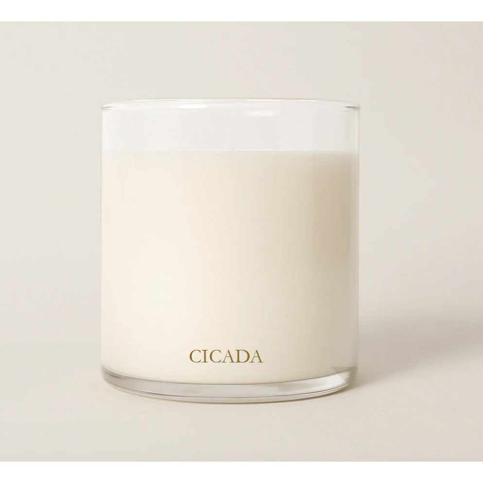 Candle in a glass jar with 'CICADA' branding on a light background