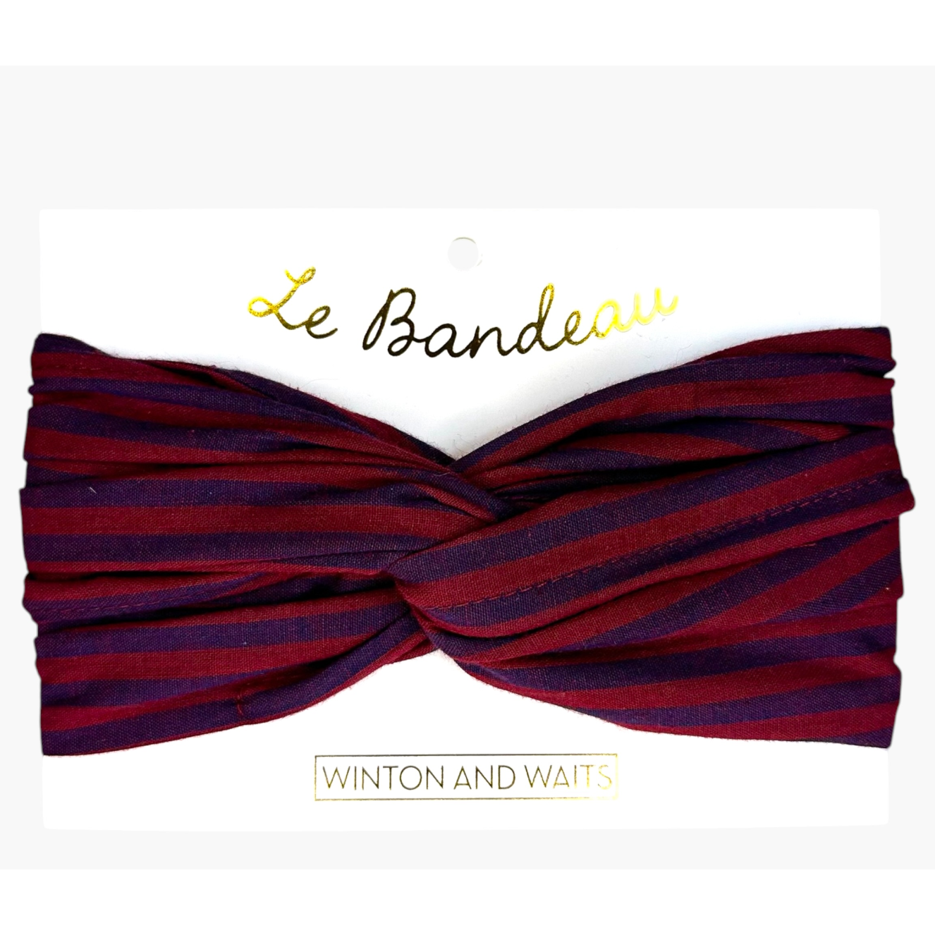 A twisted fabric headband with horizontal burgundy and dark purple stripes, presented on a white display card with gold foil text reading 'Le Bandeau' and 'Winton and Waits'.