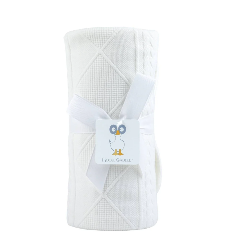 White quilted blanket with a brand tag on a white background