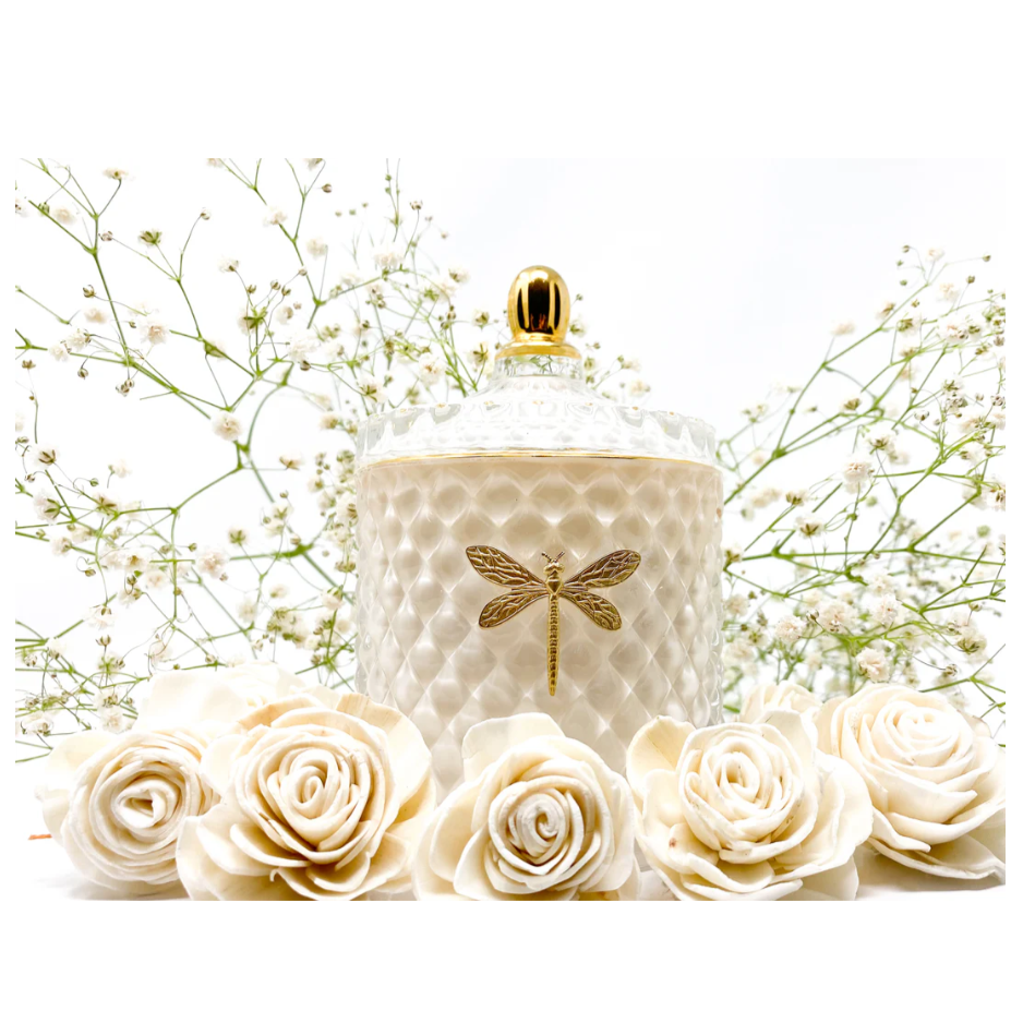 Decorative jar with dragonfly design surrounded by white roses and delicate greenery on a white background