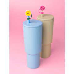 Two colorful cups with decorative toppers on a pink background