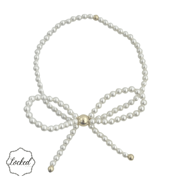 A singlestrand pearl bracelet arranged in a bow shape with gold-toned metal accents at the center and tips, shown on a plain white background.