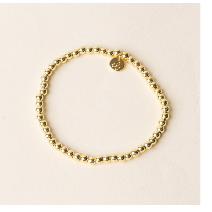 Gold beaded bracelet on a beige background