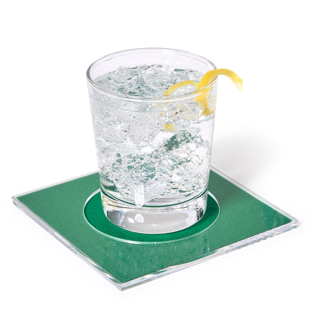 A clear square drink coaster with a circular cutout, shown holding a clear glass filled with ice and a yellow lemon twist garnish on a white background.