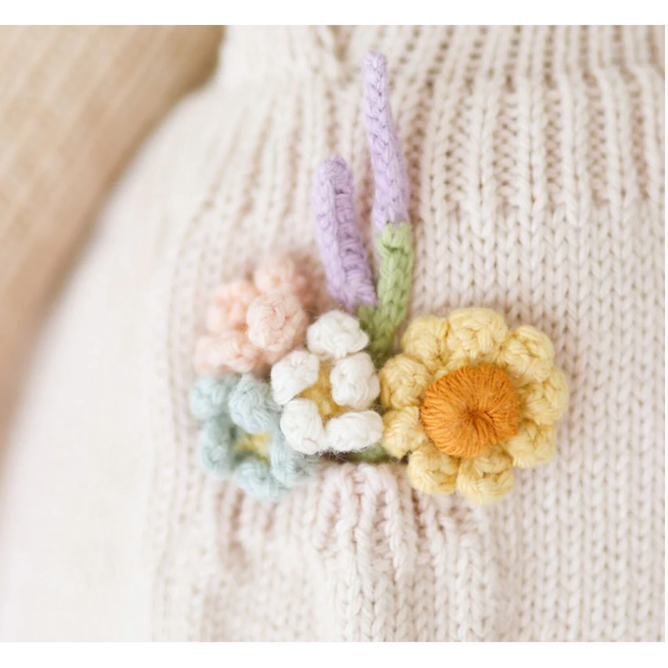 Knitted flowers in pastel colors on a textured fabric background