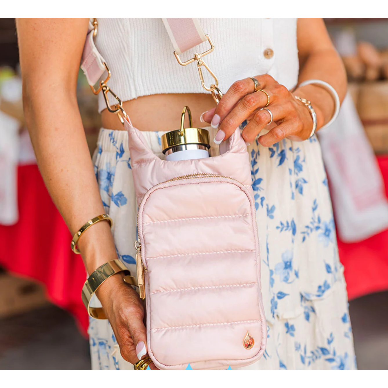 Person holding a pink crossbody bag with a gold strap