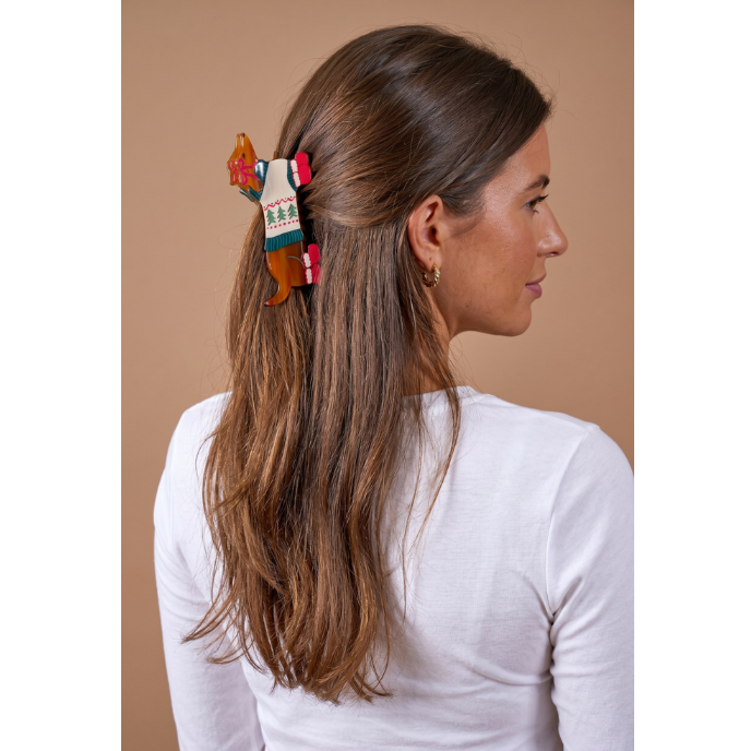 A woman with long brown hair is shown from the back and side profile, wearing a colorful decorative hair claw clip. The clip features a white center with green text reading 'Peach Blossom' and red and orange decorative elements.