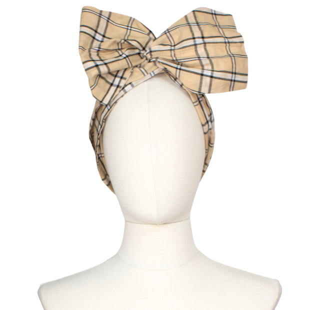 A beige plaid headwrap with a large bow, displayed on a white mannequin head against a white background.