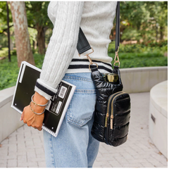 Person holding a black puffer bag and a tablet outdoors