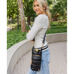 Woman holding a black quilted handbag in an outdoor setting