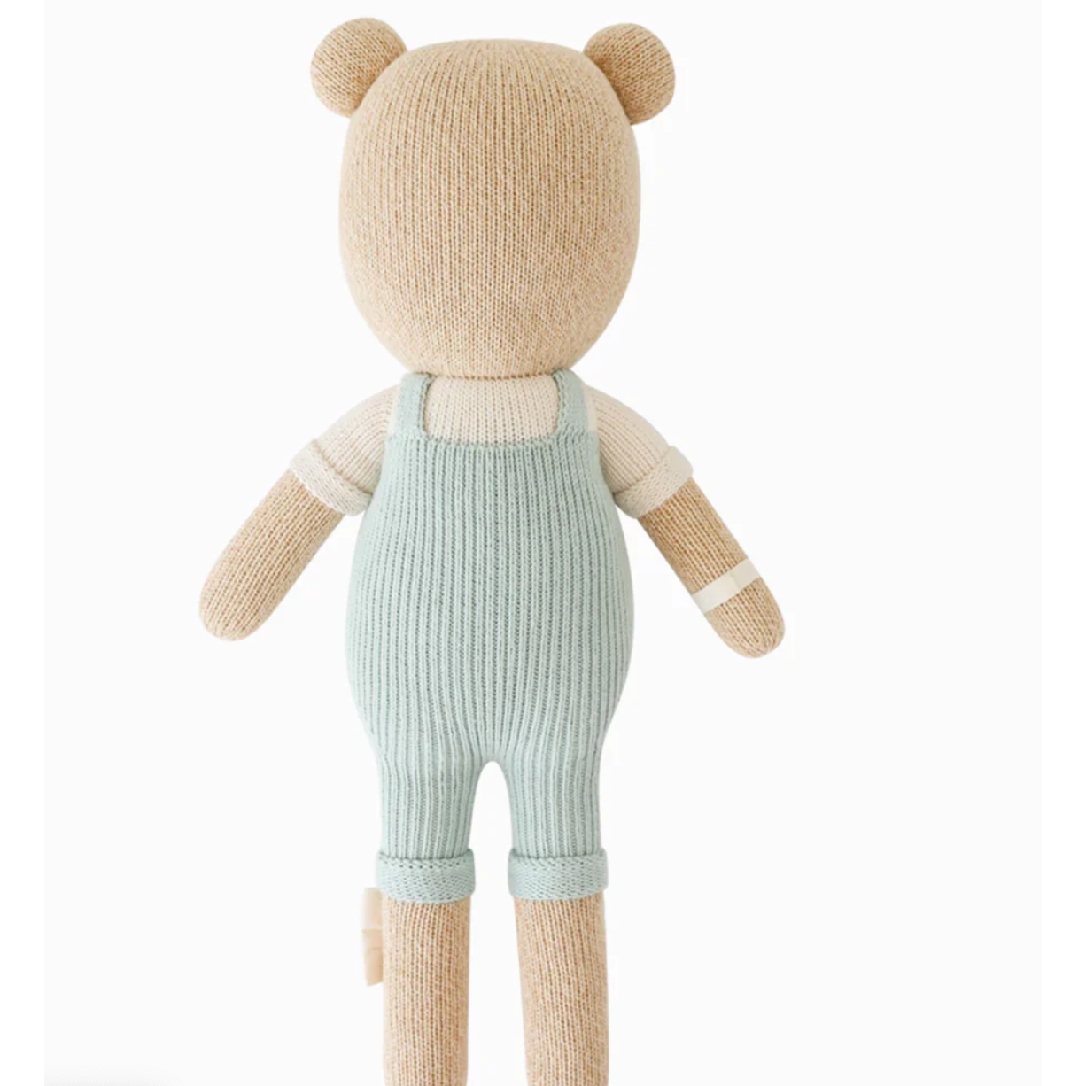 Knitted teddy bear wearing a light blue romper on a white background