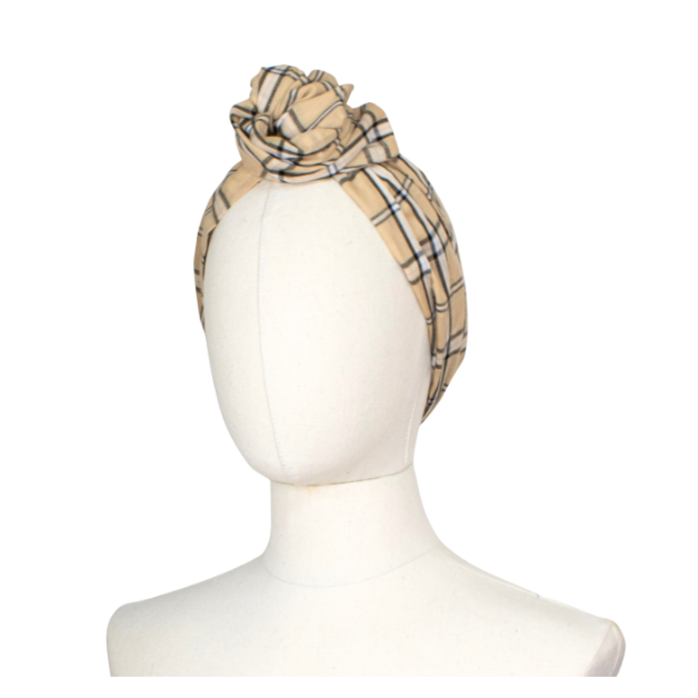 A beige plaid headband styled in a large top knot, displayed on a white mannequin head against a plain white background.