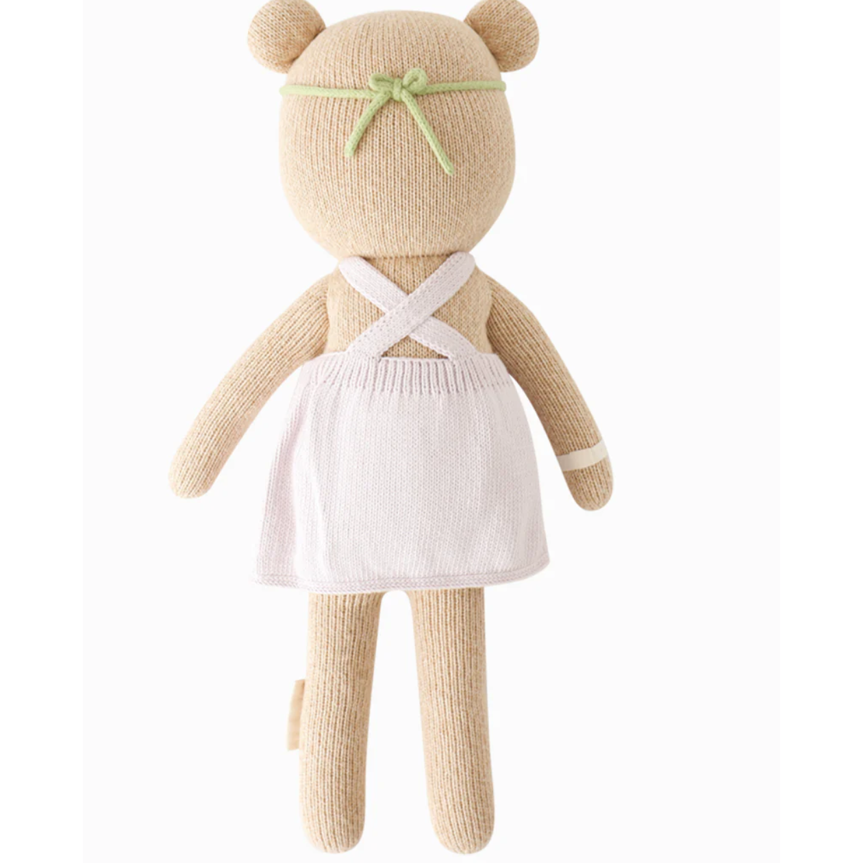 Knitted teddy bear in a white dress with a green bow on a white background