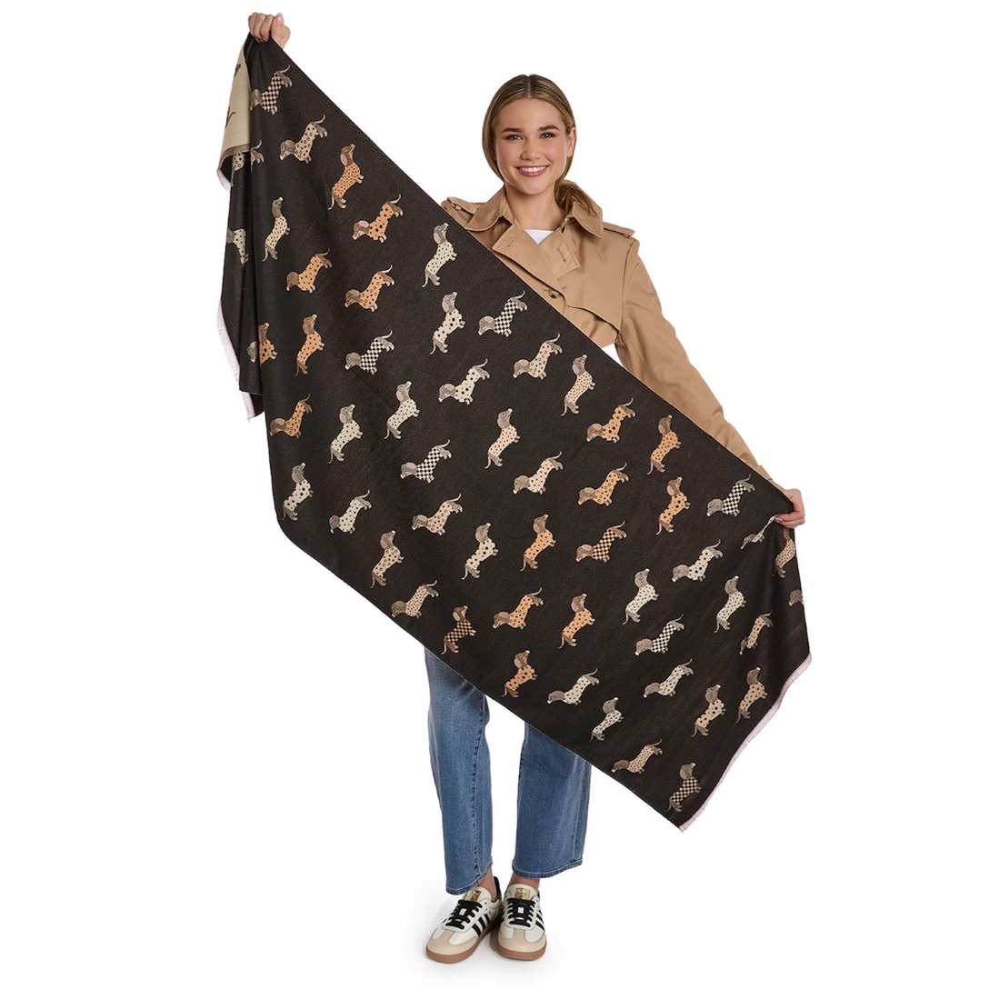 Person holding a large black scarf with dog patterns on a white background