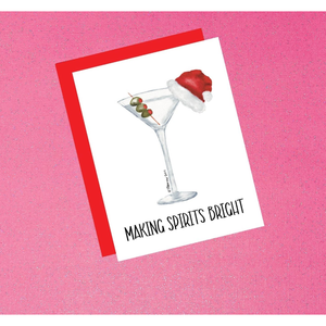 Card with a martini glass wearing a Santa hat and olives on a pink background