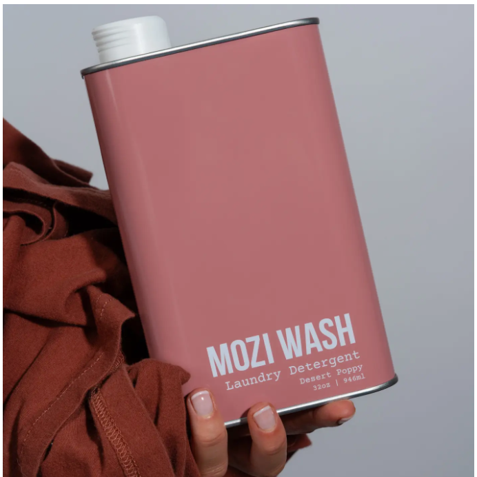 Pink can of Mozi Wash laundry detergent with a brown garment in the foreground