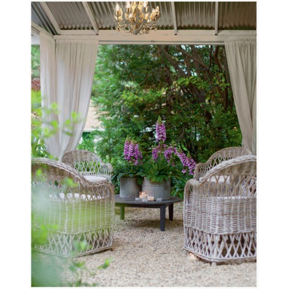 Outdoor patio with wicker chairs, a table, and a chandelier under a pergola.