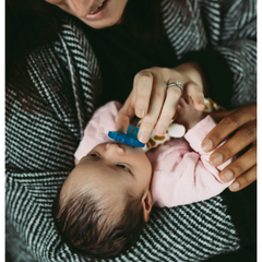 Baby being held by a person with a blue teething ring
