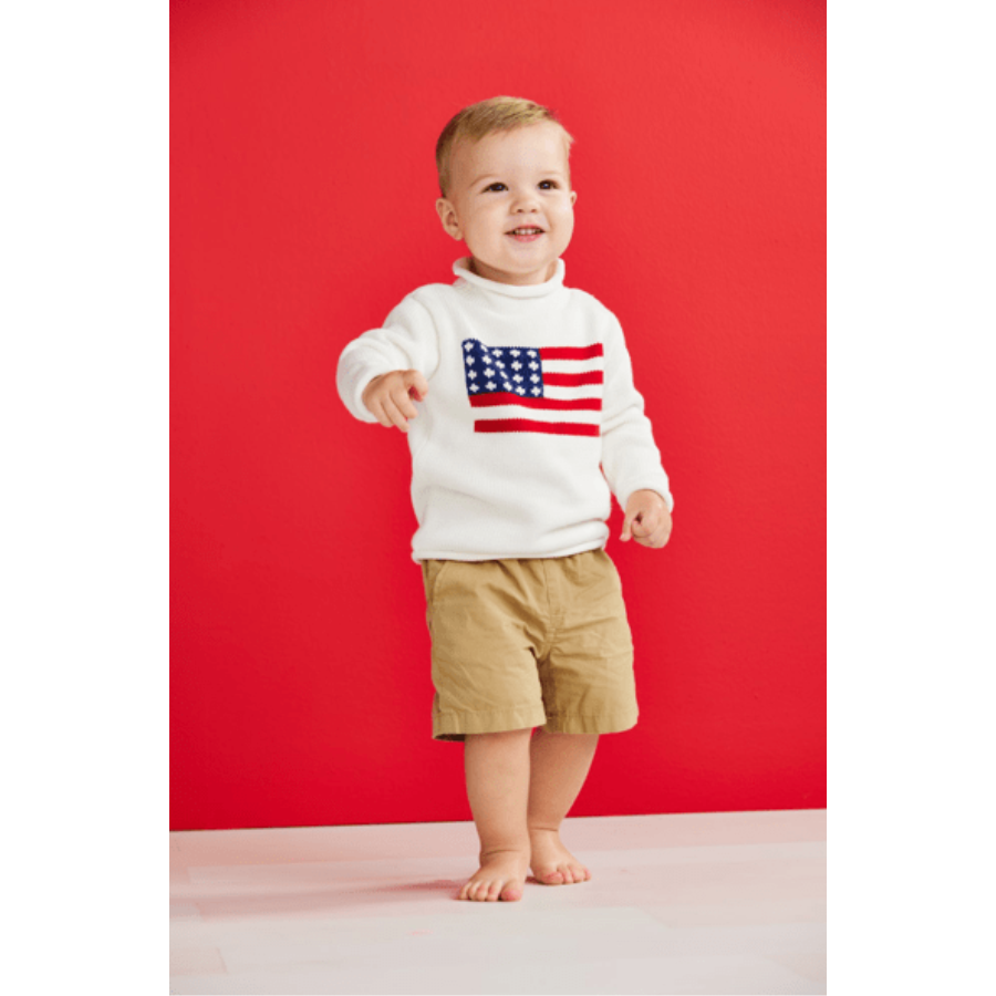 Child wearing a white sweater with an American flag design against a red background