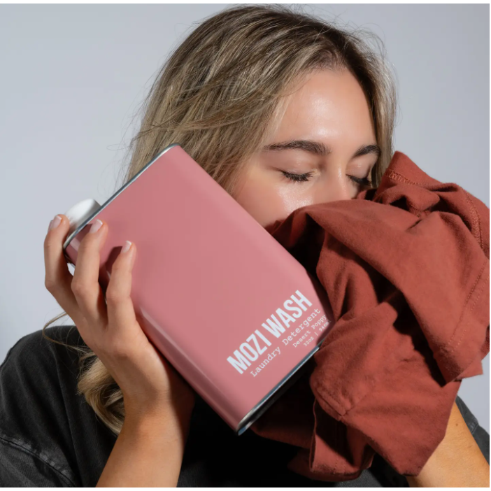 Person holding a pink device labeled 'MOZI WASH' with a red garment.
