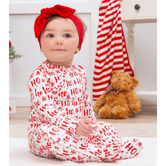 Baby wearing a red and white outfit with 'HO HO HO' text, sitting on a light-colored floor.