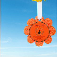 Orange flower-shaped sponge with SpongeLLE branding against a blue sky background