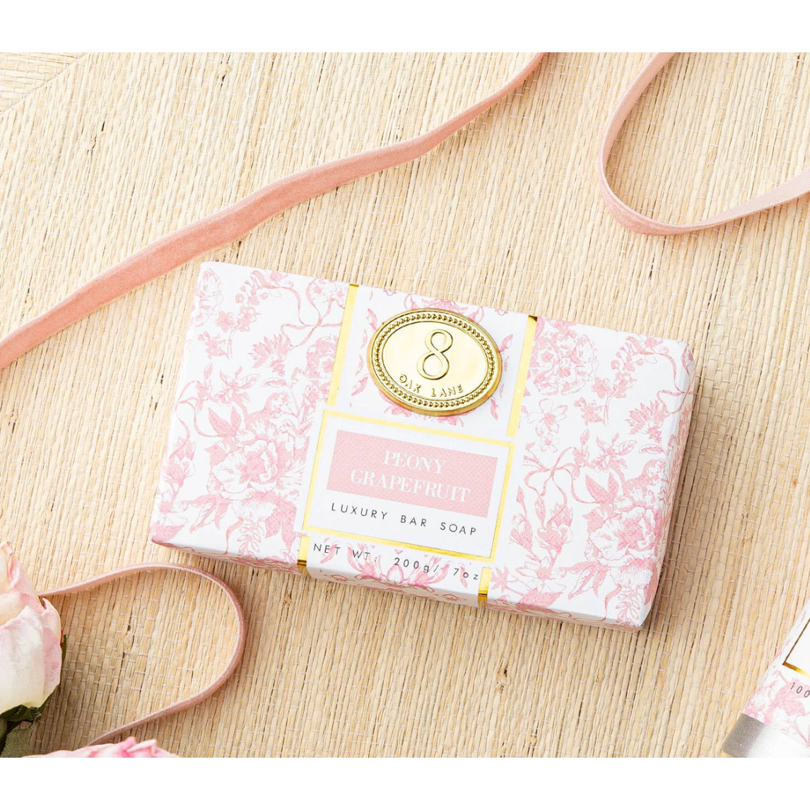 Luxury bar soap in a decorative pink packaging on a wooden surface with a pink ribbon.