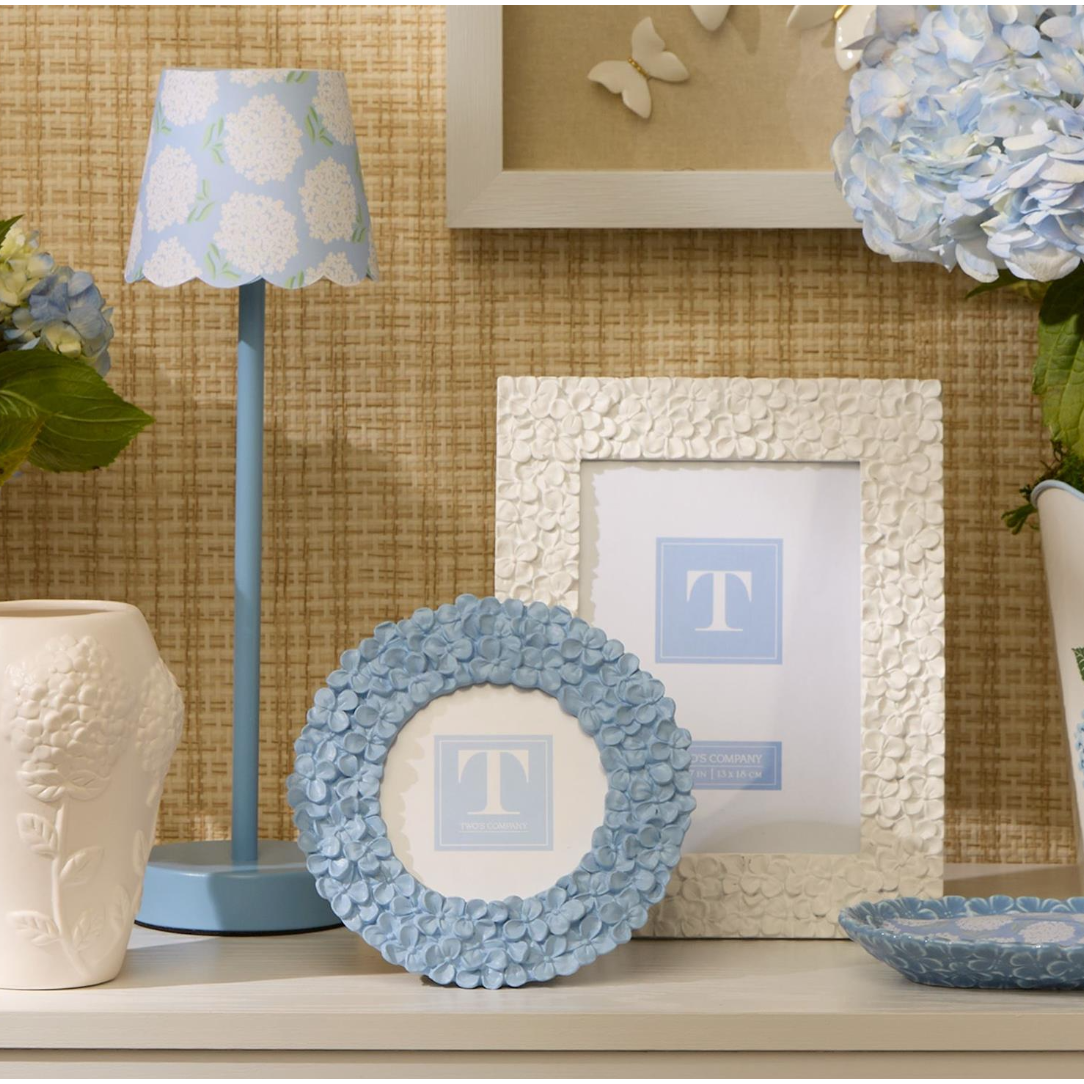 Decorative items including a lamp, framed picture, and floral arrangements on a shelf.