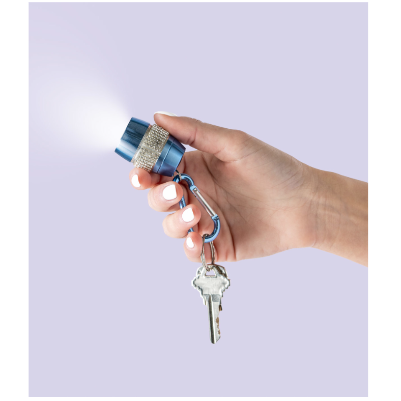 Hand holding a blue flashlight with a keychain on a light purple background