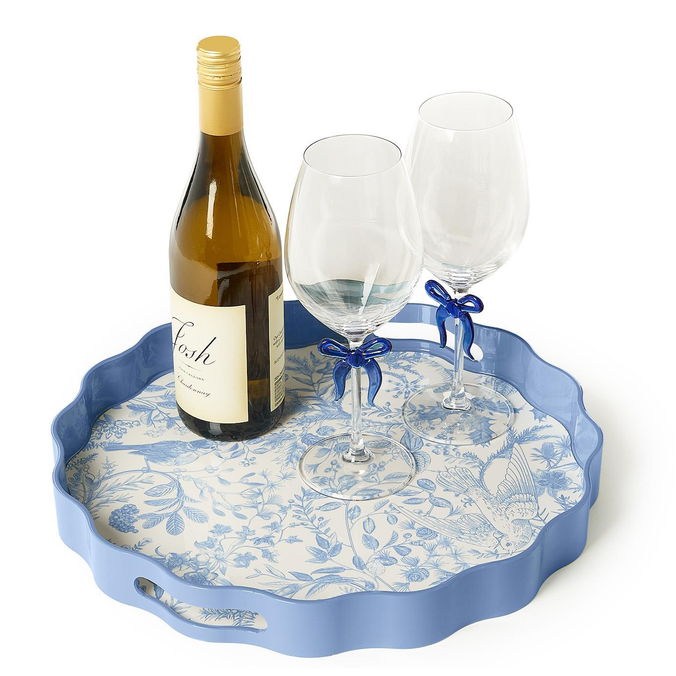 A scalloped blue serving tray with a floral blue-and-white patterned liner, styled with a wine bottle and two clear wine glasses tied with blue ribbons, on a white background.