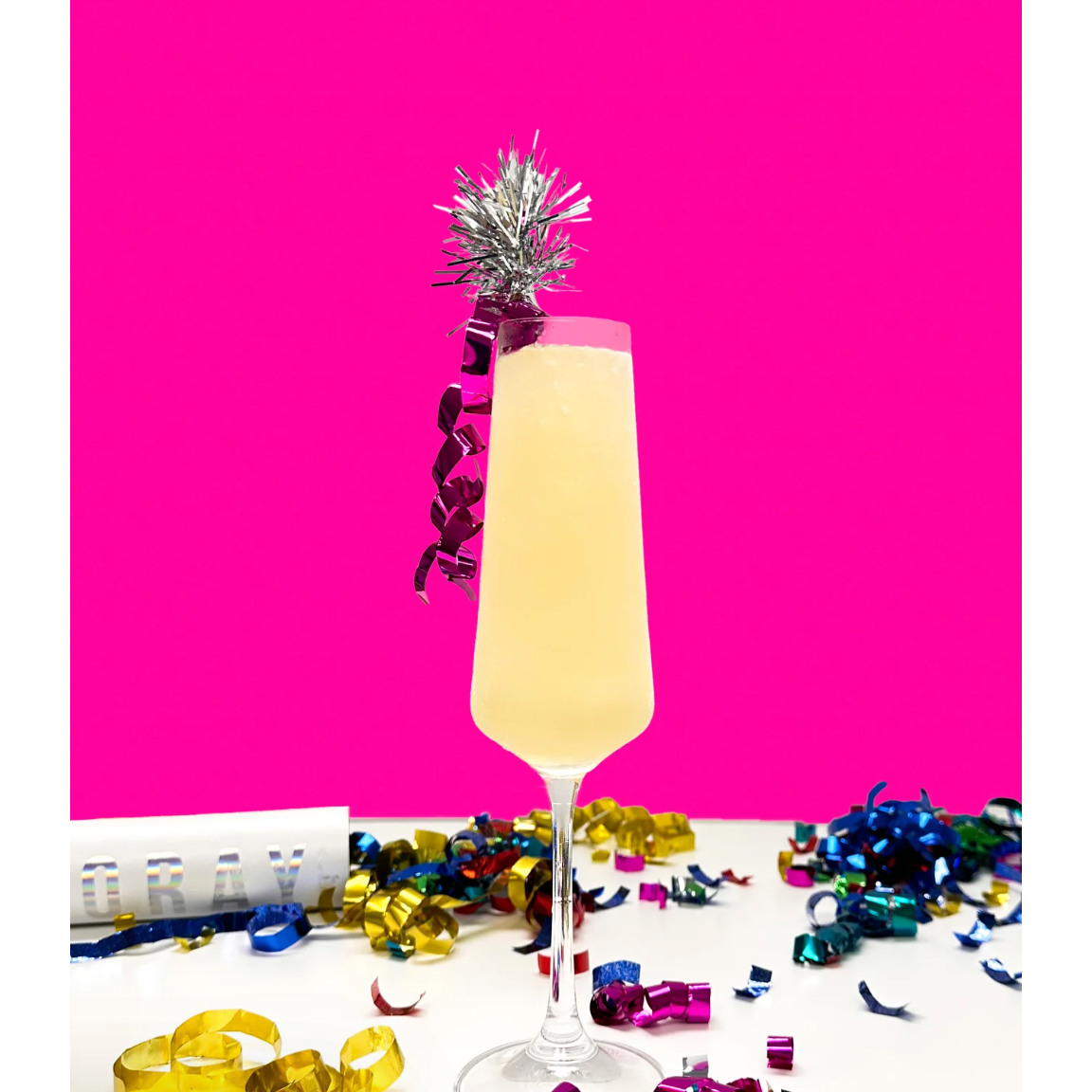 Champagne flute with a cocktail and festive decorations on a pink background