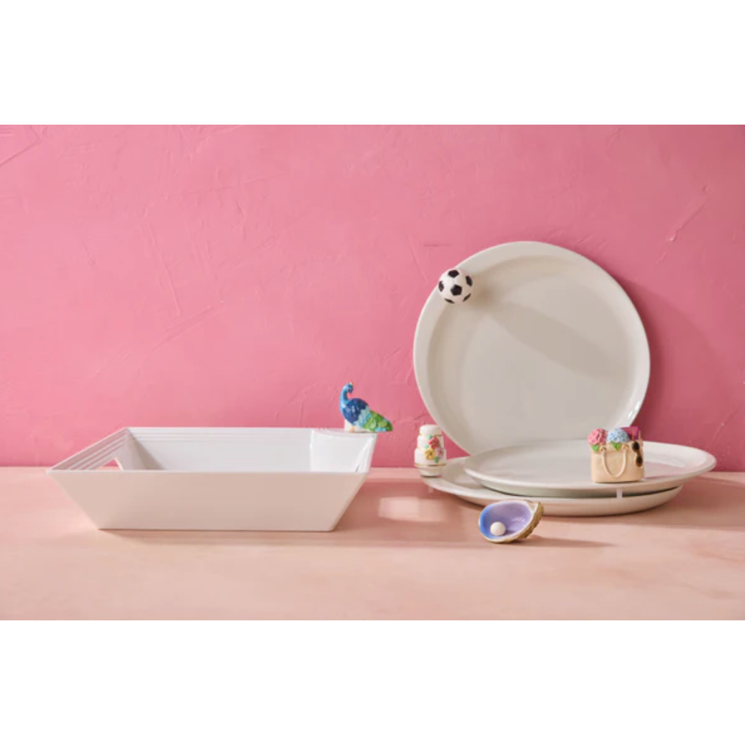 White ceramic plates and a square dish on a pink surface with a pink background