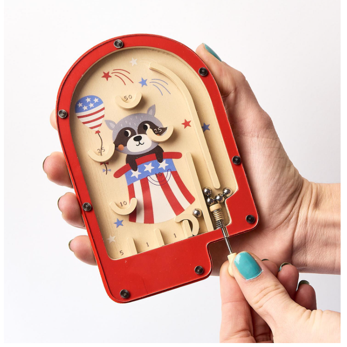Wooden mechanical model of a dog with American flag design held by a hand.