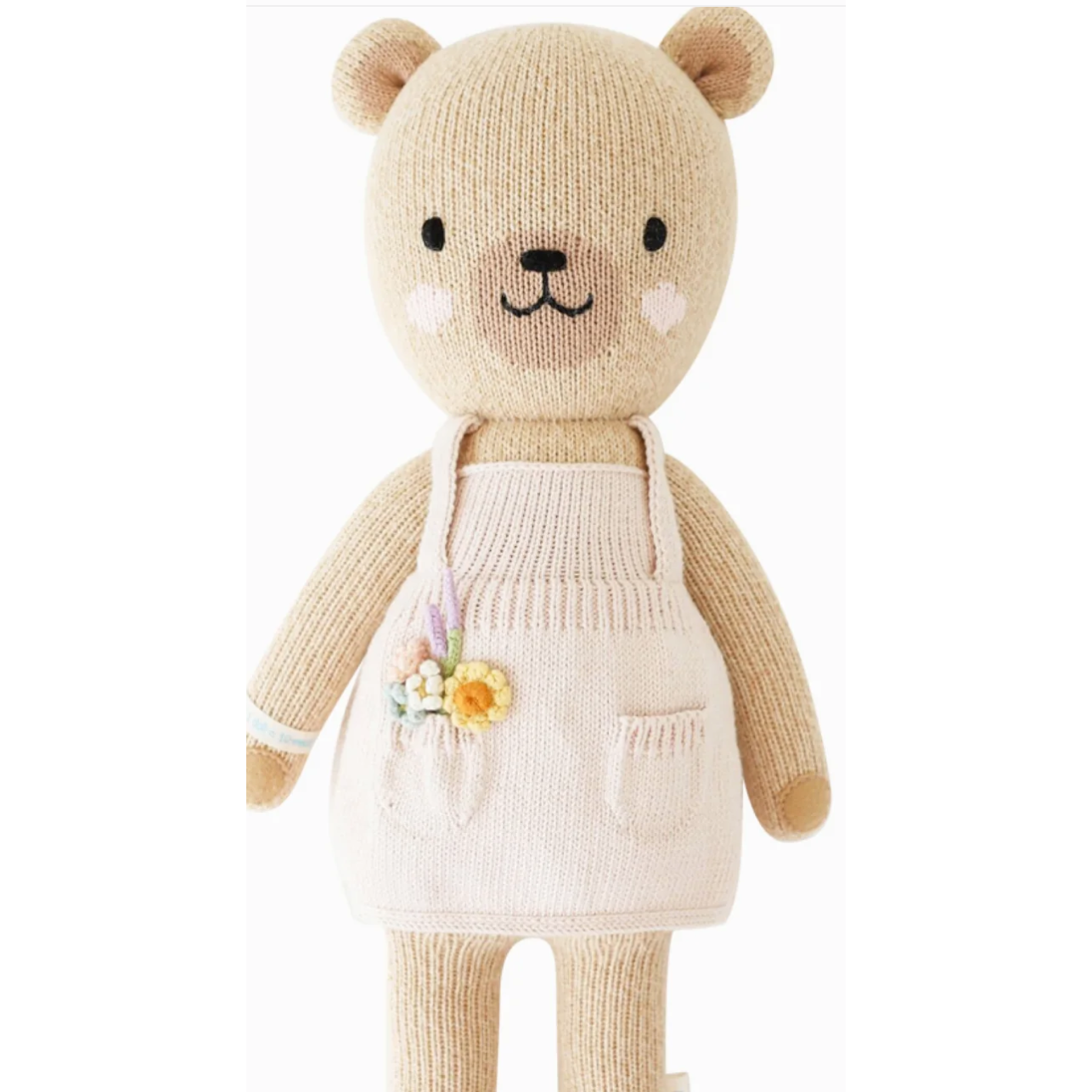 Knitted teddy bear wearing a white apron with a floral design on a white background