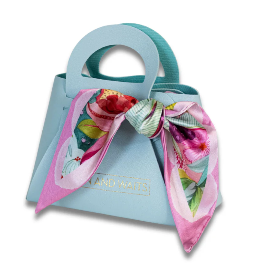 Light blue handbag with a floral scarf draped over it on a white background