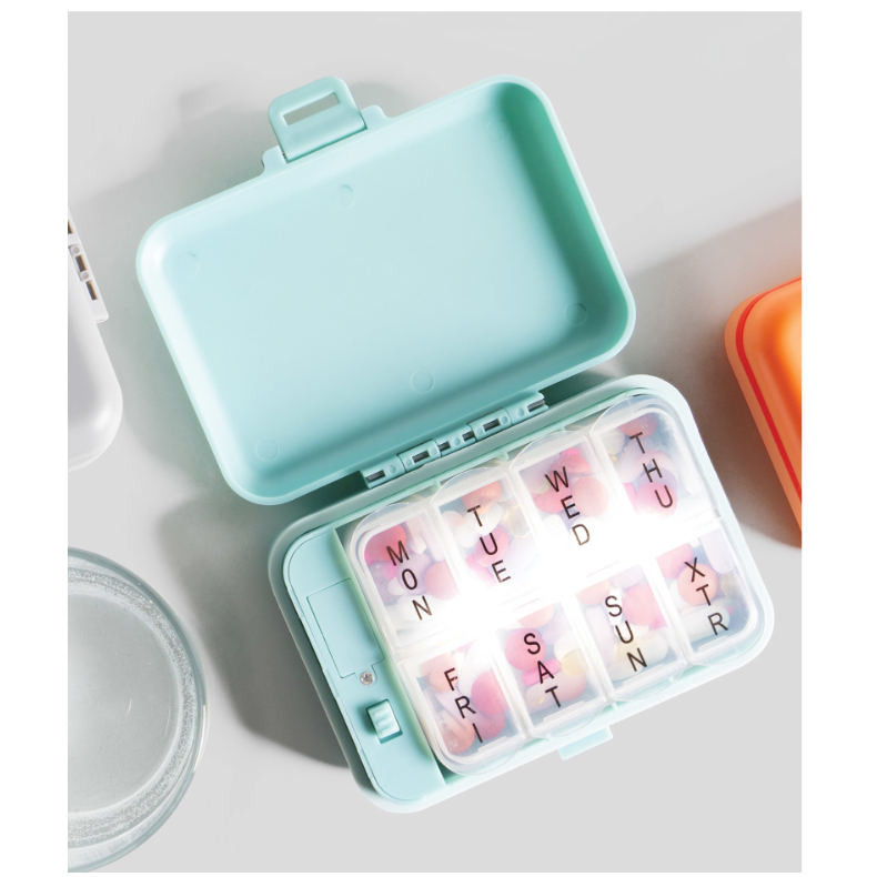 Light blue pill organizer with days of the week labels on a white background