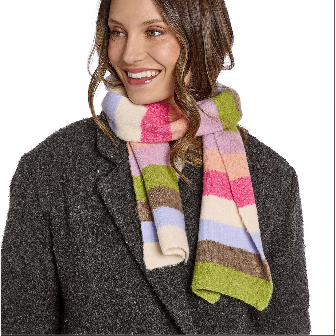 A woman wearing a chunky knit striped scarf in pastel shades of pink, green, beige, brown, and light blue, paired with a dark gray textured coat against a plain white background.