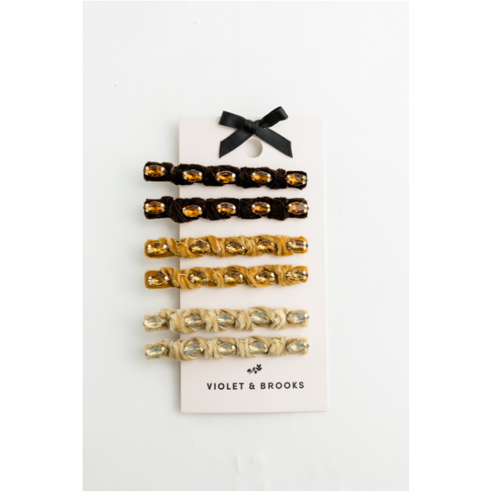 A set of three hair clips from Violet & Brooks, displayed on a white card with a black ribbon bow. The set includes black and gold, gold and gold, and cream and silver color combinations.