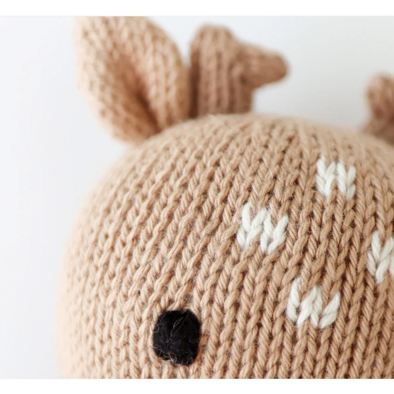 Knitted deer hat with antlers and a black nose on a white background