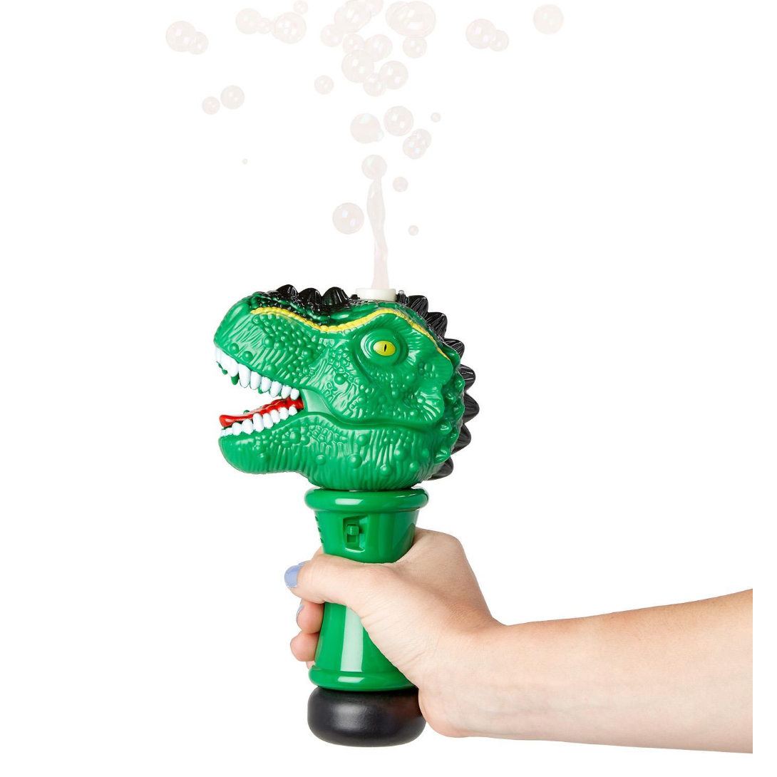 Green dinosaur-shaped bubble blower being held with bubbles around it on a white background
