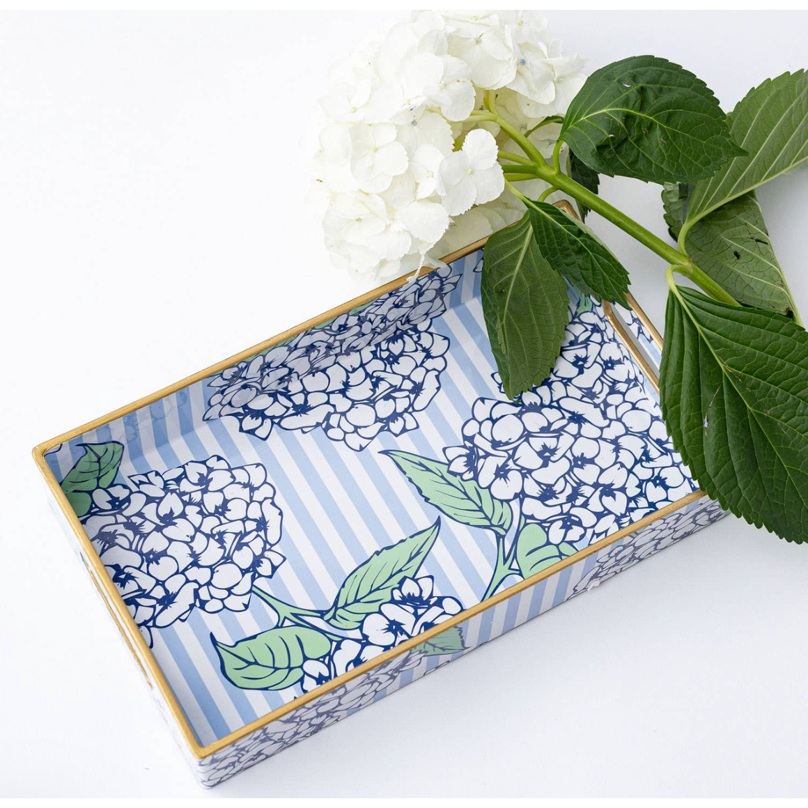 Decorative tray with floral pattern on a white surface with green leaves.