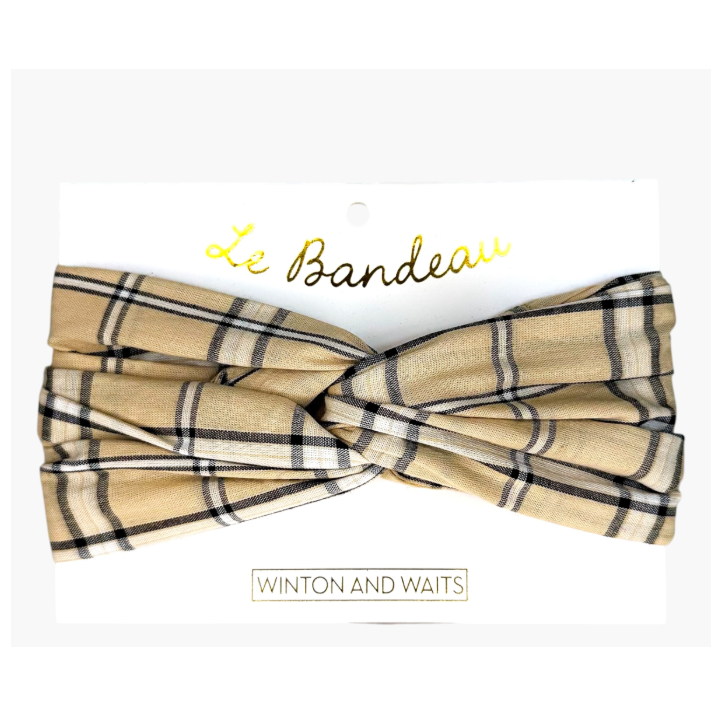 A beige plaid twist-front bow tie headband by Winton and Waits, presented on its white retail backing card with gold 'Le Bandeau' lettering.
